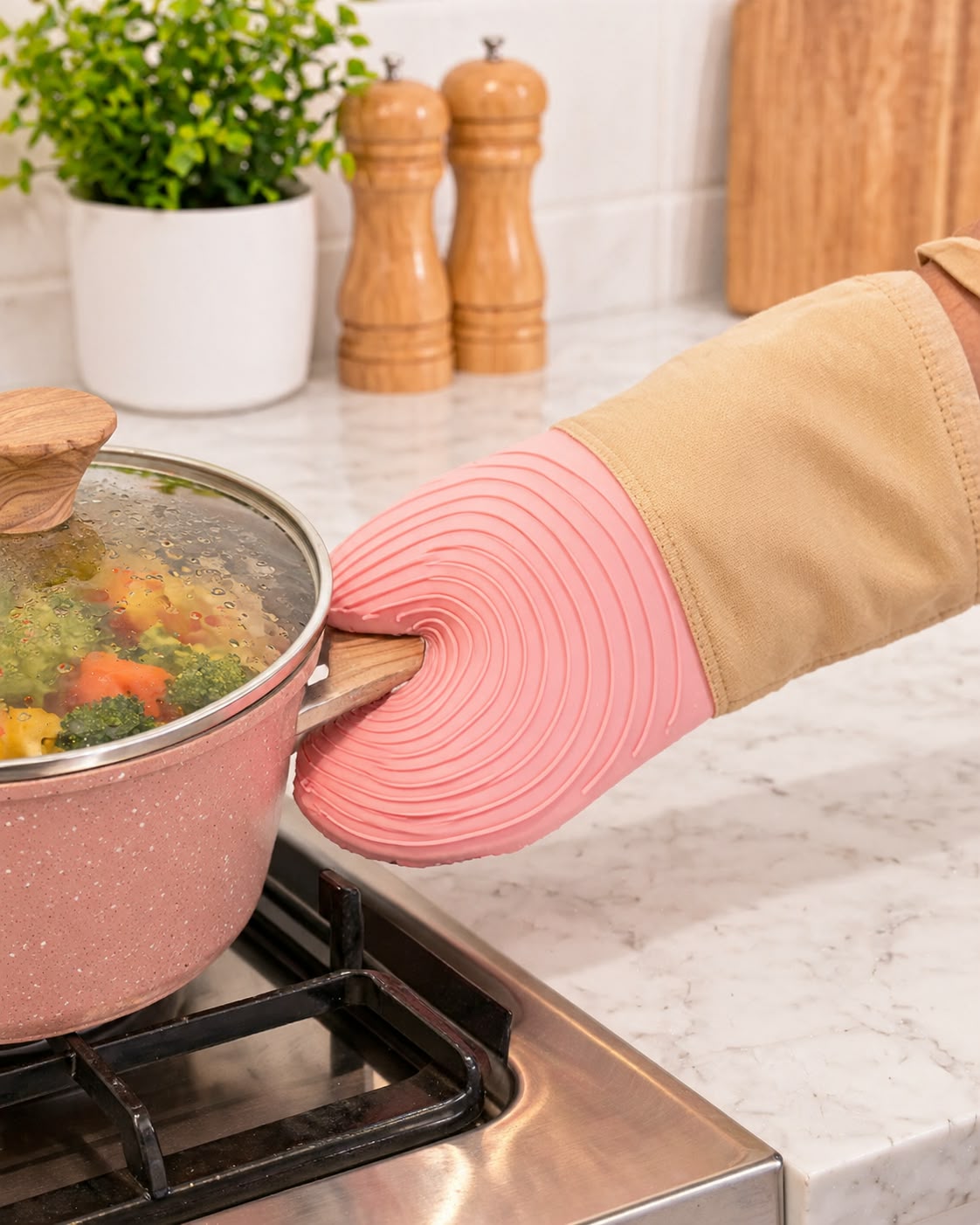 Pink silicone oven mitt with beige fabric cuff holding pot