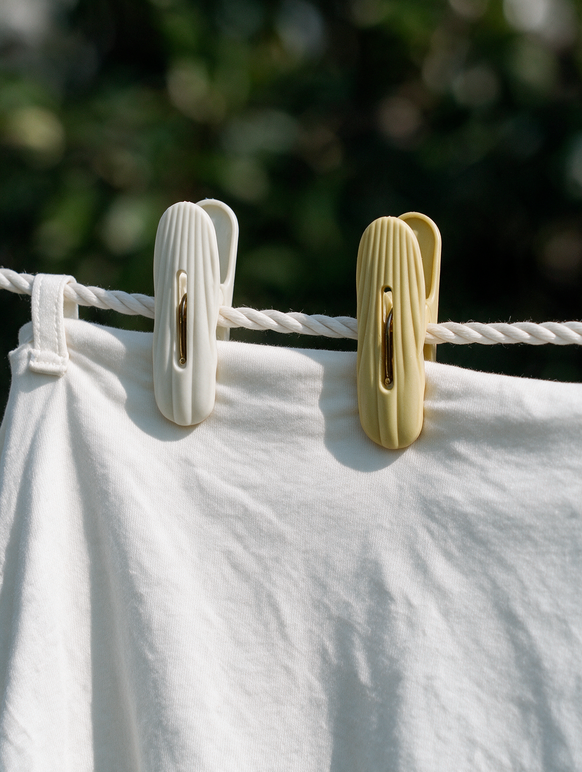 Ribbed laundry clothes pegs holding a white garment on a clothesline