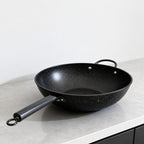 Vallena professional-grade black granite coated fryer with a long handle and dual side loops on a kitchen counter.