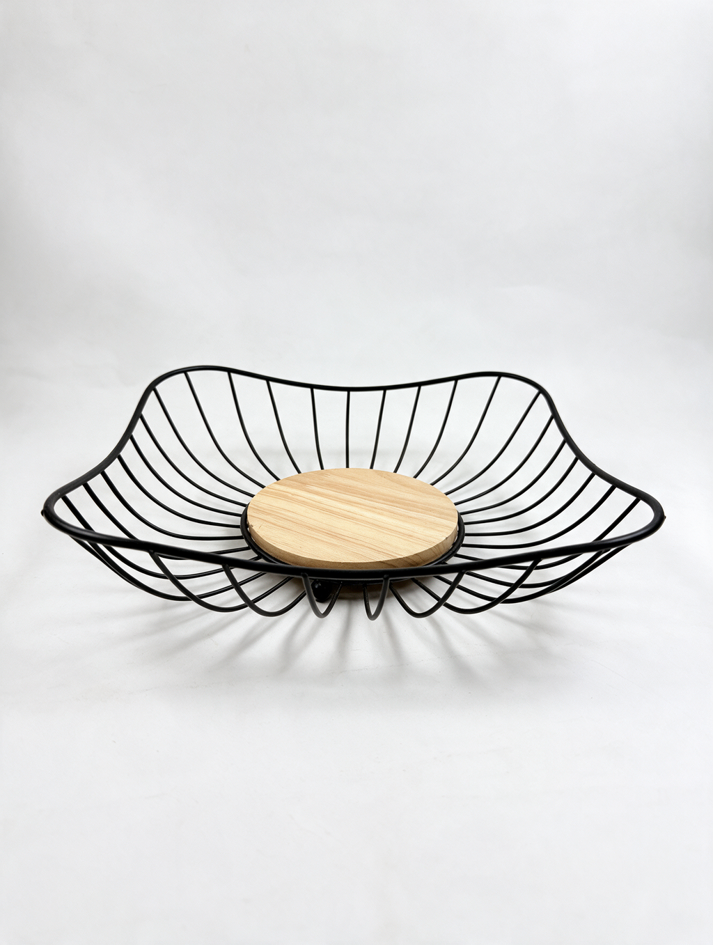 Black metal fruit basket with wooden center on white background