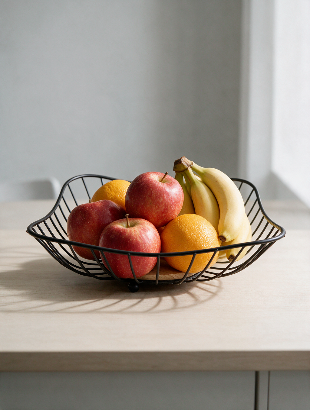 Black metal fruit basket with fruit on a table