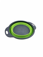 Small collapsible silicone colander in green collapsed on white background